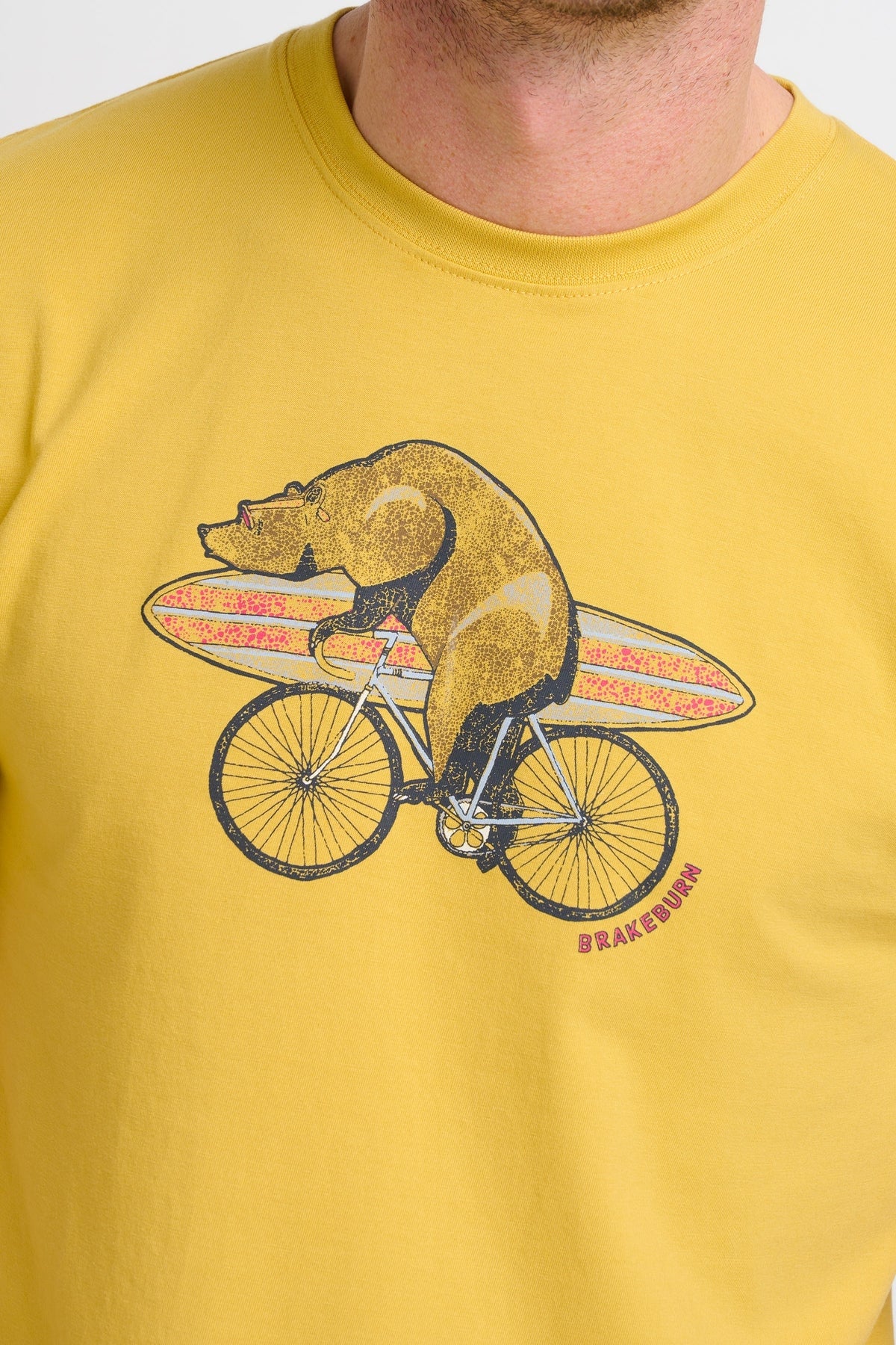 Men's tee of a print of a bear on a bicycle with a surfboard