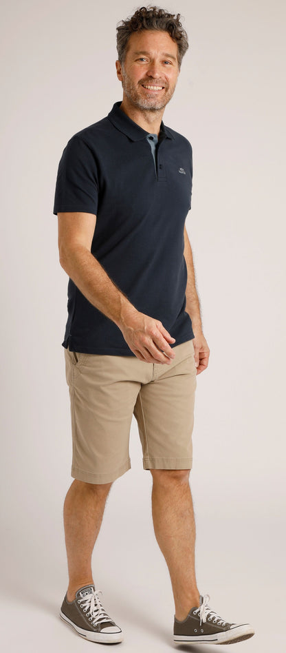Man wearing Weird Fish mens Rayburn chino shorts Taupe Grey paired with a black polo shirt and grey sneakers